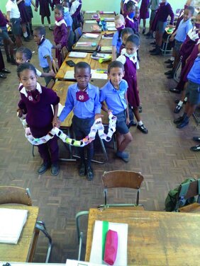 Grundschülerinnen und Grundschüler stehen um Tische herum in einer Schule in Namibia