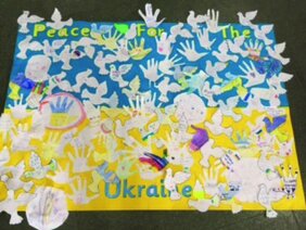 Selbstgebasteltes Plakat mit weißen Händen und Tauben auf der Ukraine-Flagge