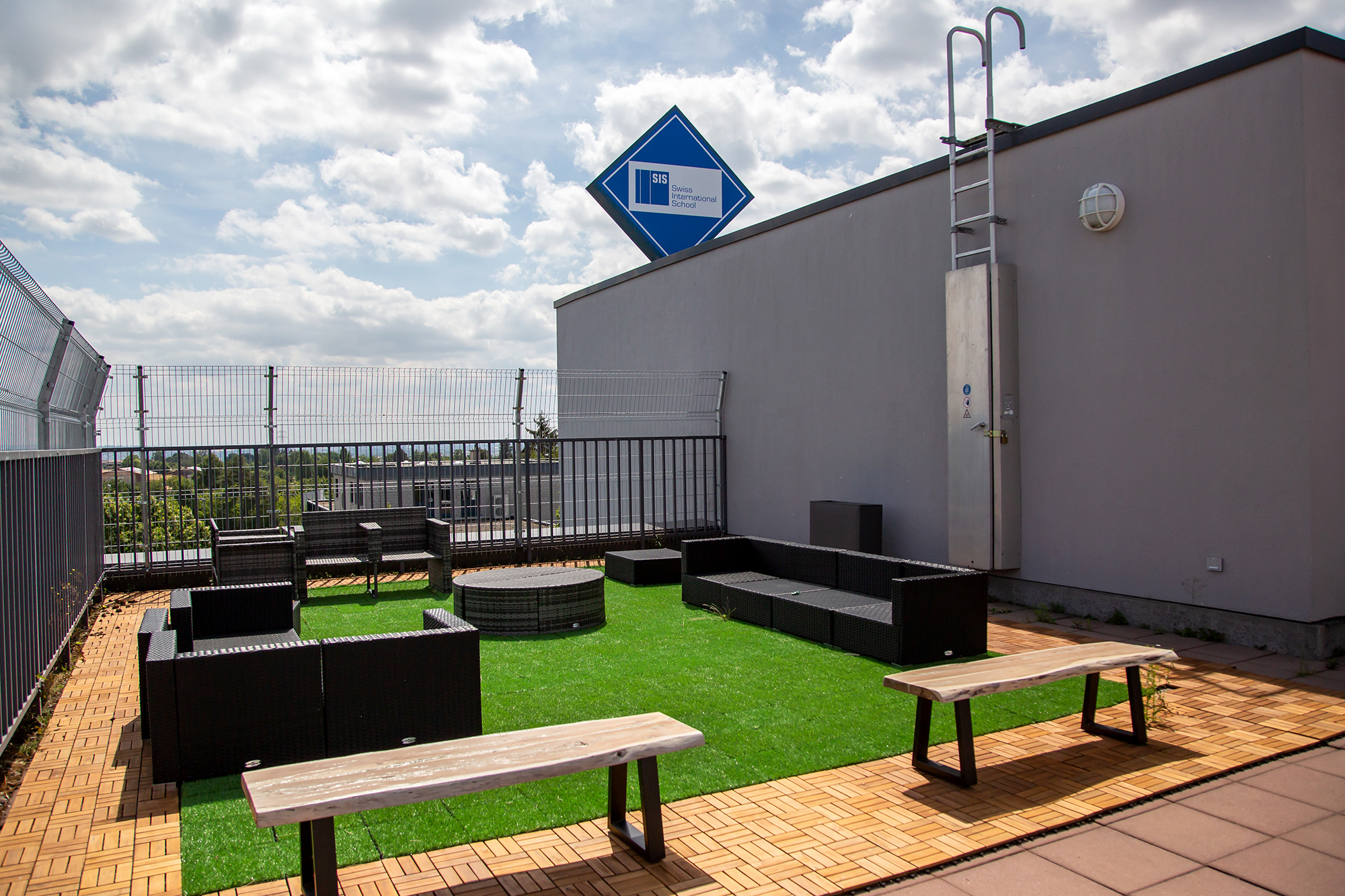 The roof terrace with a green field and benches on it.