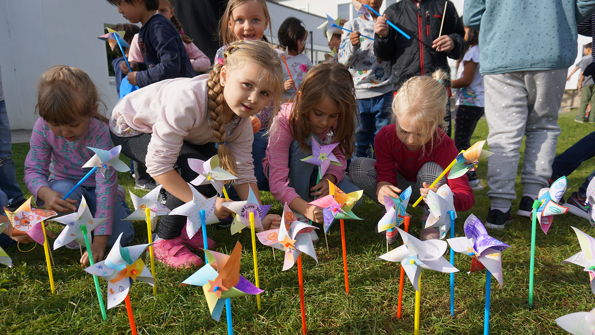 Children set up small pinwheels on the lawn.