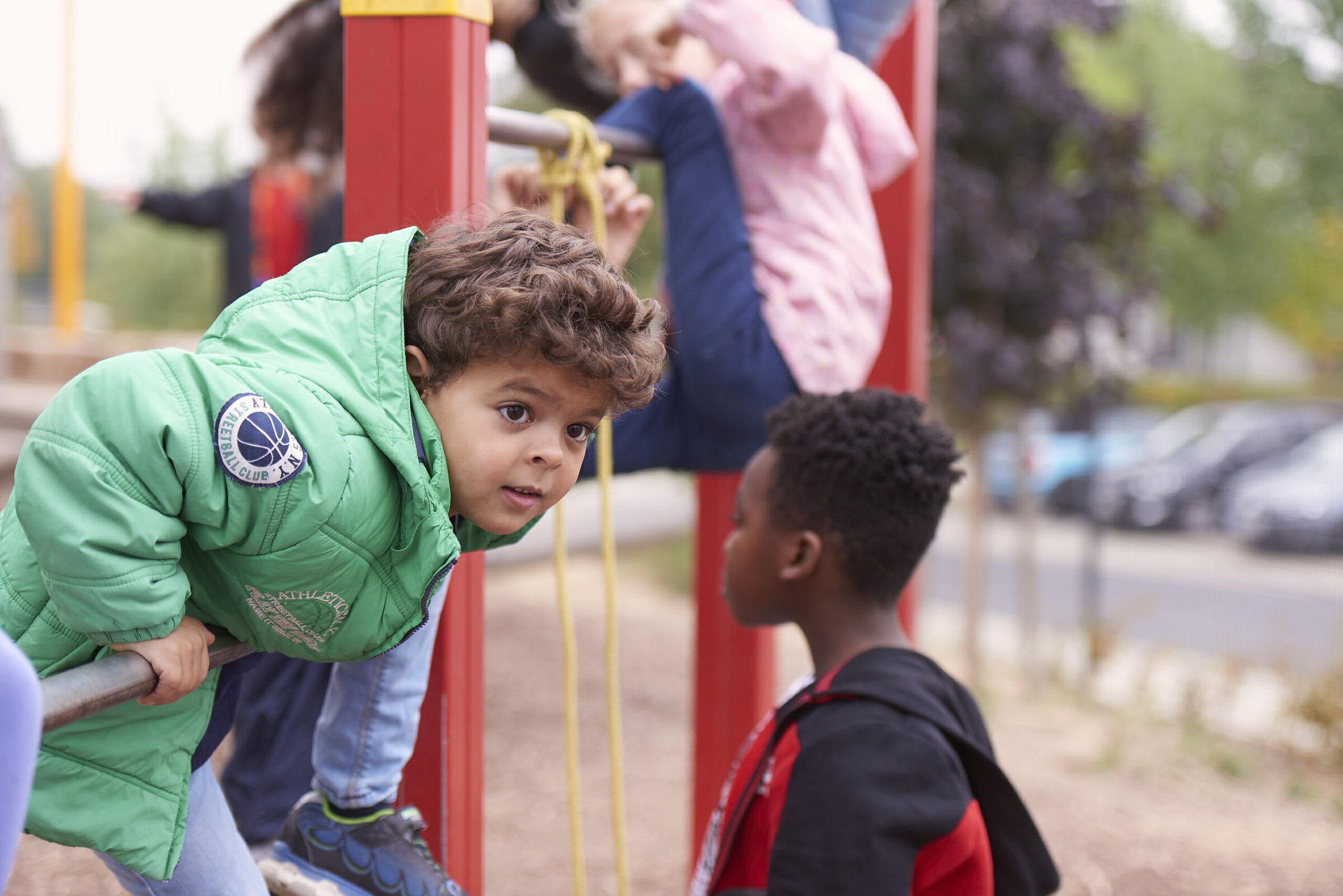 Kinder auf dem Spielplatz. Ein Junge stützt sich auf eine Reckstange.