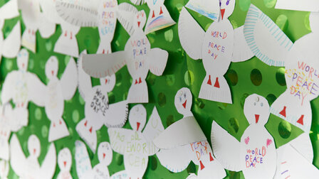 Crafted white birds stick on a green background.