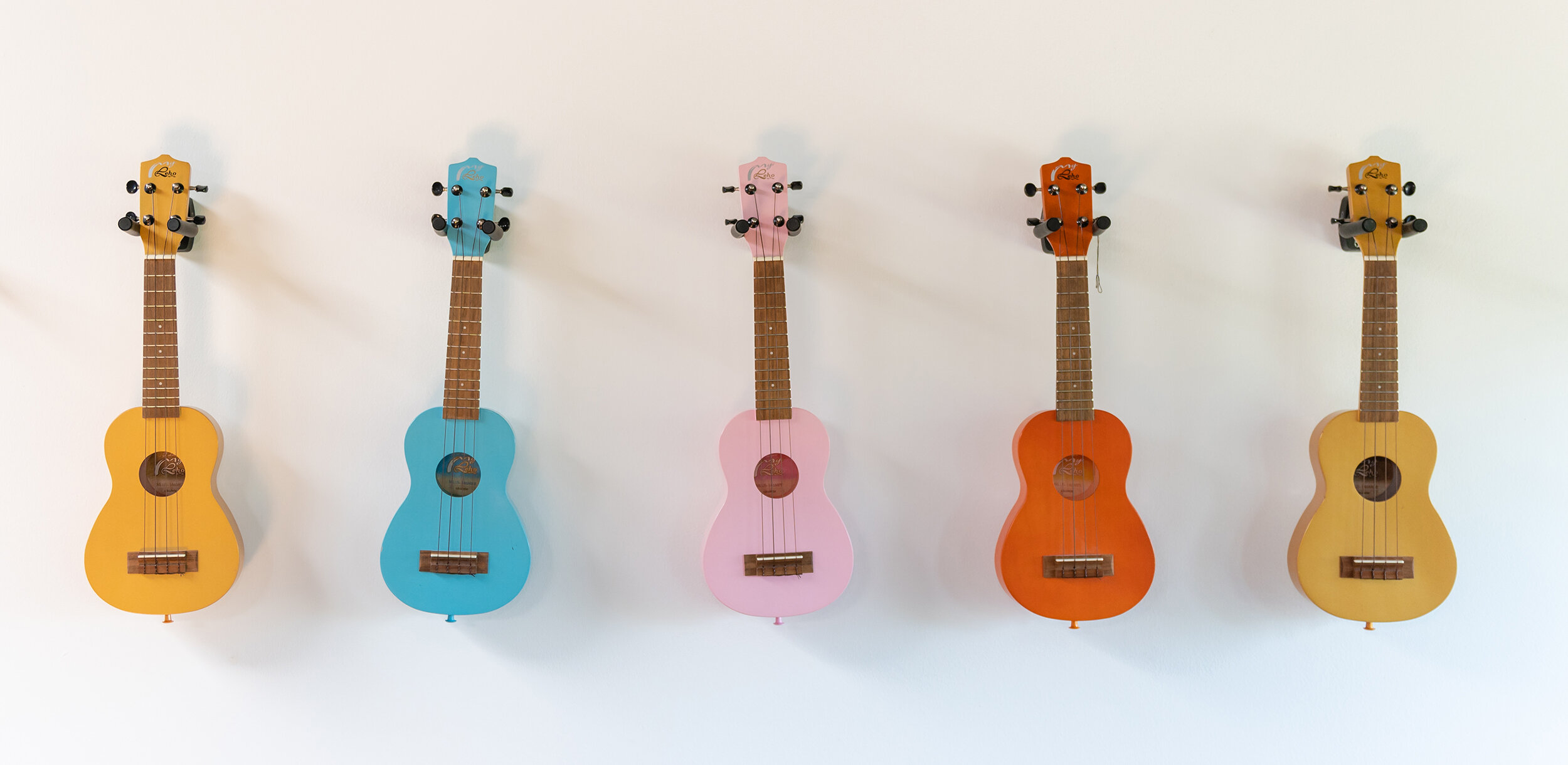 Ukuleles hang in a row on the wall.