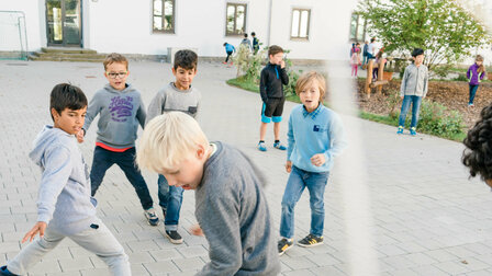 Students during the break in the school yard. A playground can be seen in the background.